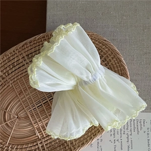 Detailed macro view of yellow organza scrunchie with layered lace edges on wicker tray