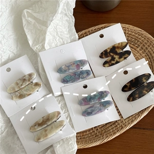 Lot de barrettes ovales élégantes en acétate avec motifs marbrés sur une carte