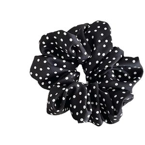 Classic black and white polka dot scrunchie made of silky fabric with elegant folds