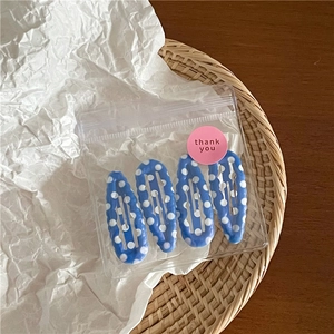 Detail van vier blauwe haarspelden met stippen in een geschenkverpakking met een bedanksticker