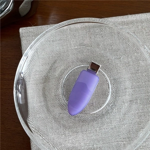 Close-up of purple matte resin hair clip on a glass plate with linen background