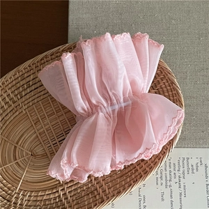 Detail of pink organza pleated cuff with delicate lace edges on a woven basket