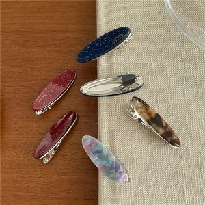 Vue détaillée des barrettes vintage en acétate avec texture marbrée et clips en métal bec de canard