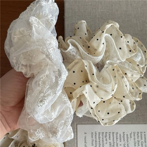 Gros plan sur chouchous en dentelle blanche et beige à pois avec broderie florale