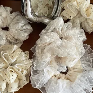 Lot de chouchous en dentelle brodée et tulle à pois beige crème sur surface en bois