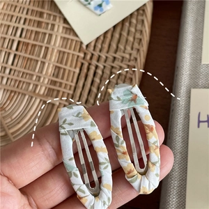Close-up of handmade floral fabric hair clips with yellow pattern and metal inner core
