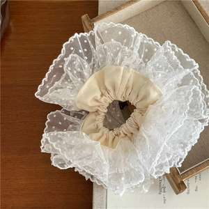 Détail d'un chouchou en dentelle blanche à pois avec une bande intérieure en satin beige