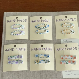 Detail view of 6 sets floral fabric hair clips in oval and rectangular shapes on card