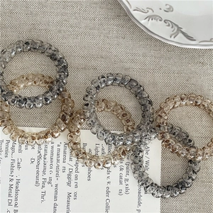 Vue à plat d'élastiques à cheveux spirale motif léopard gris et marron sur lin