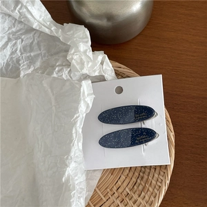 Détails de barrettes bleues en acétate avec paillettes dorées et inscription élégante