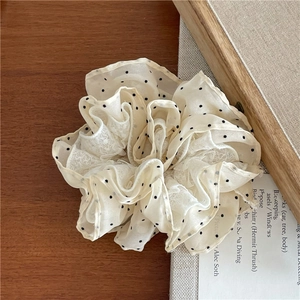Vue détaillée du chouchou en tulle beige à pois avec dentelle sur table en bois