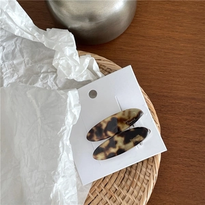 Détail de barrettes élégantes en acétate avec motif écaille et lettrage doré chic