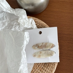 Vue détaillée de barrettes ovales en acétate avec texture marbrée sur un plateau