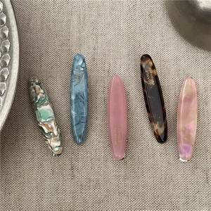 Tortoiseshell and marble pattern acetate hair clips set on linen fabric background