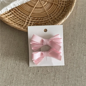 Dettaglio di fermagli per capelli a fiocco rosa in tessuto a coste su cartoncino