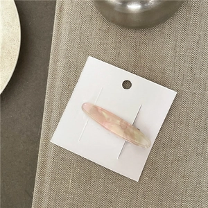 Detailed macro view of pink marble texture on oval acetate hair clip shown on card