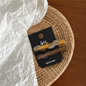 Gros plan de barrettes à cheveux ondulées en acétate ambre et marron sur carte