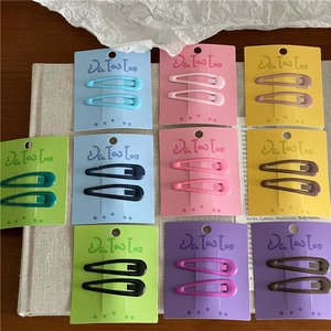 Detail showing ten pairs of matte colorful cream-toned 6cm snap hair clips on cardboards