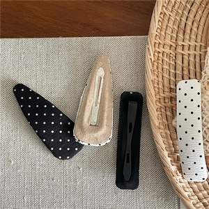 Detail of black and white polka dot fabric hair clips with metal base and beige lining