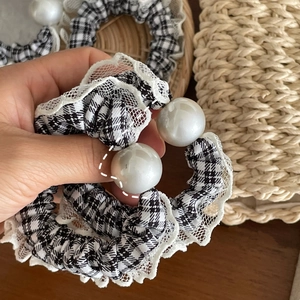 Detail of checkered fabric scrunchie with white lace trim and large faux pearl accents