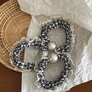 Detail of plaid fabric scrunchies with white lace trim and large faux pearl accents