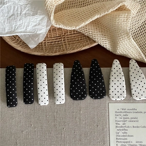 Detailed overhead view of 8-piece black and white polka dot hair clips set on a woven base