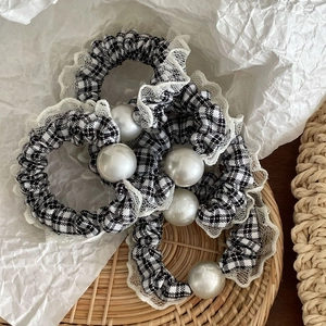 Detail of checkered fabric scrunchies with white lace edges and large faux pearls