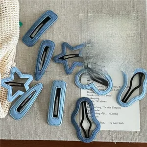 Detail of assorted denim fabric hair clips in star and heart shapes on a rustic cloth