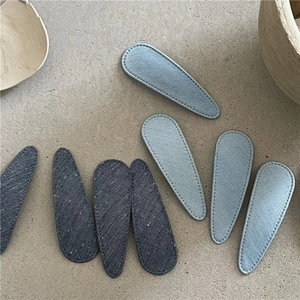 Detail of denim fabric hair clips in blue waterdrop shapes with visible stitching