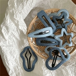 Detail view of denim fabric hair clips in star and heart shapes with needlework stitching