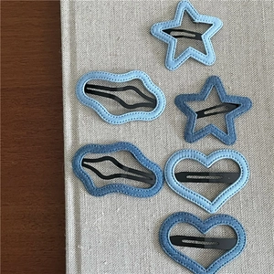 Detail of denim fabric hair clips featuring star, heart, and cloud shapes with fine stitching