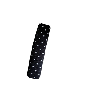 Minimalist black hair clip with white polka dots pattern and rounded rectangle design