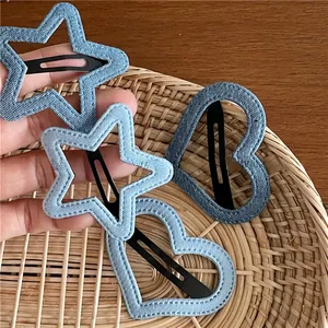 Detailed close-up of blue denim star and heart hair clips on a woven tray background