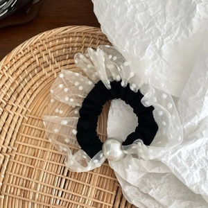 Close-up of mesh polka dot scrunchie featuring a large pearl and layered lace ruffles