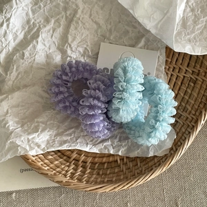 Detailed macro view of light purple and pale blue pleated mesh scrunchies on a woven tray