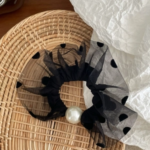 Close-up of black polka dot mesh hair scrunchie featuring an elegant pearl detail