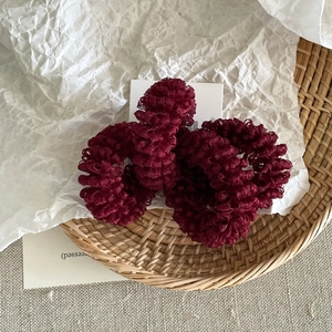 Close-up of wine red honeycomb mesh scrunchies in a woven basket with a soft texture