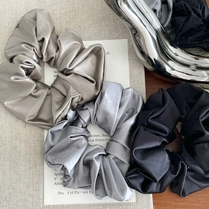 Detailed close-up of champagne, grey, and black satin scrunchies in a premium set