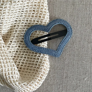 Detailed view of heart-shaped blue denim hair clip with black metal snap clip