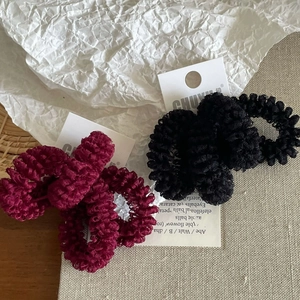 Close-up of wine red and black ruffled mesh fabric hair scrunchies on elegant packaging