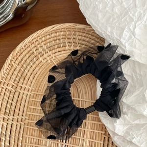 Detailed close-up of a black polka dot mesh scrunchie in a decorative woven basket