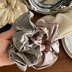 Elegant satin silk scrunchies in gray, champagne, and cream shown on a wooden table