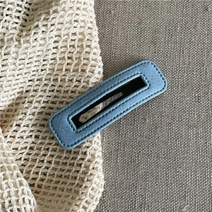 Detailed macro view of light blue fabric wrapped snap hair clip with visible stitching
