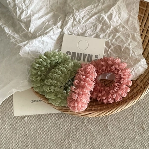 Detail of sage green and dusty rose mesh fabric scrunchies on a woven display basket