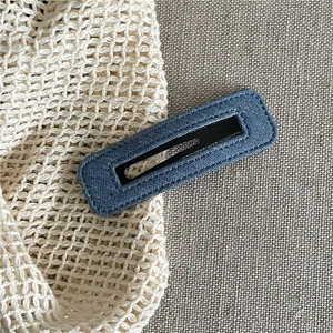 Close-up of a blue denim rectangular BB hair clip with detailed stitching on fabric