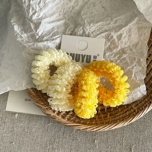 Close-up of yellow and cream mesh scrunchies with pleated texture on a display card