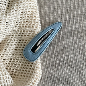 Close-up of sky blue linen fabric covered BB hair clip with fine stitching details