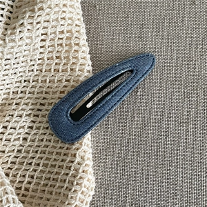 Detailed close-up of blue denim fabric hair clip showing stitch texture and metallic base