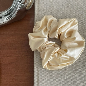 Detailed close-up showing the smooth satin texture of the champagne silk scrunchie