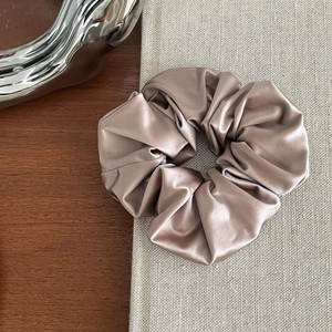 Detailed close-up of champagne satin scrunchie with elegant silk texture on wooden desk